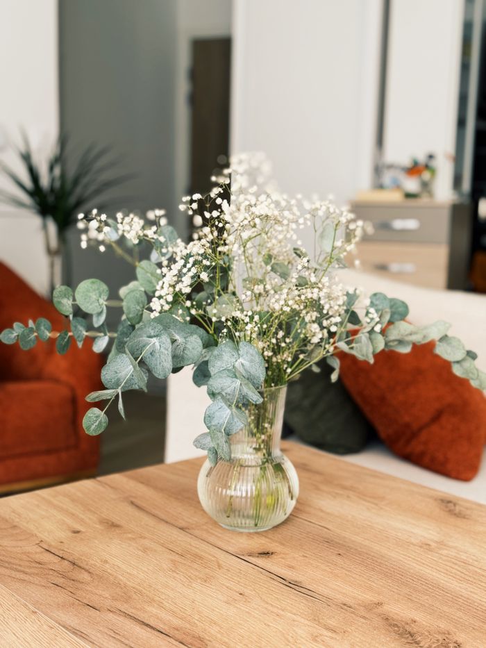 A stylish interior shot featuring white gypsophila in a glass vase placed on a wooden table.